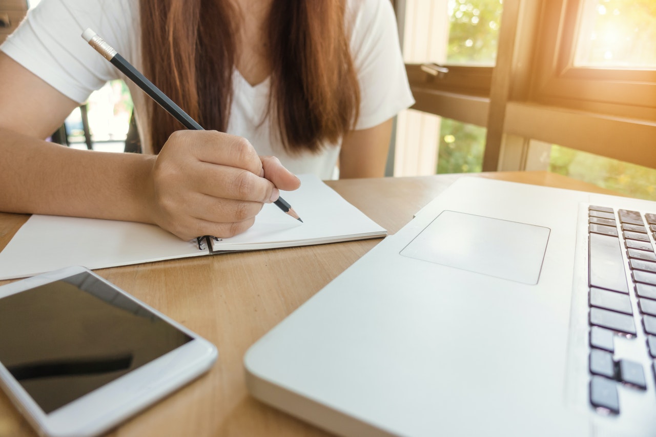 femme formation en ligne écrit au crayon de bois sur une feuille de papier devant ordinateur